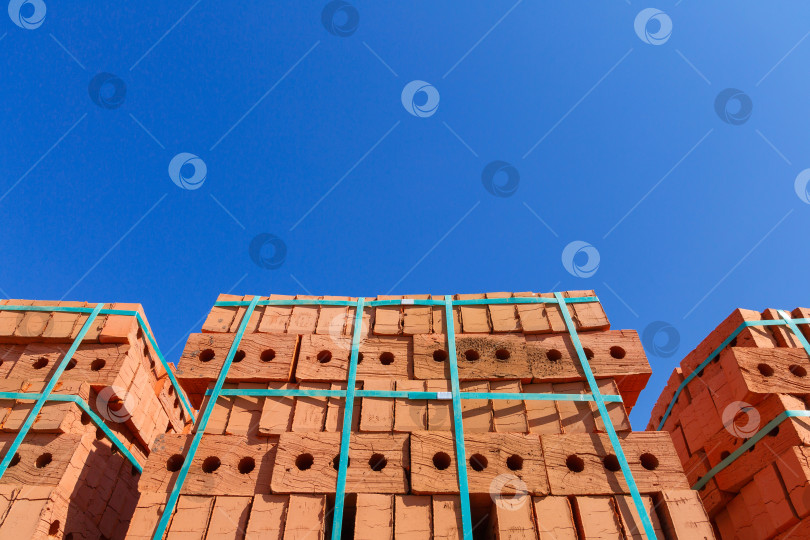 Скачать Поддоны из красного кирпича на строительной площадке на фоне неба фотосток Ozero
