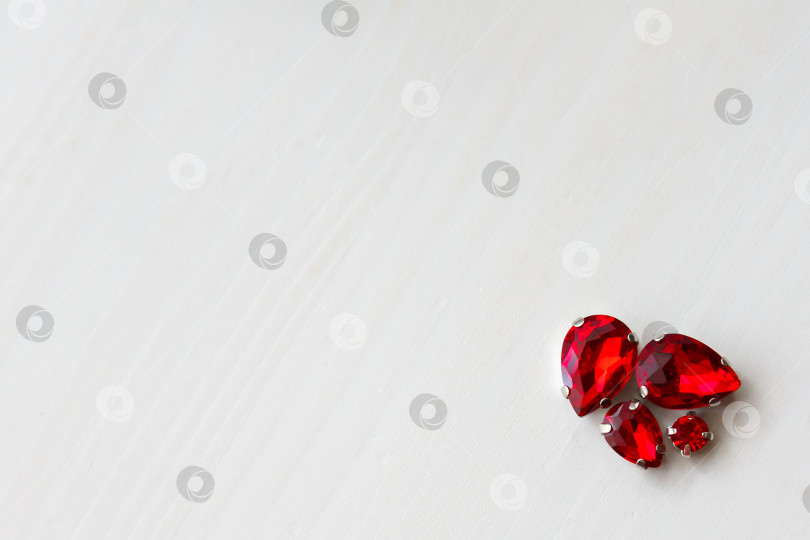 Скачать Красные камни кристаллы бусины на белом деревянном фоне в углу фотосток Ozero