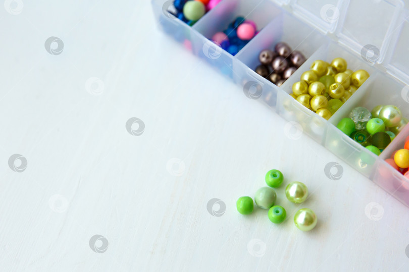 Скачать Разноцветные бусины в пластиковом контейнере на столе фотосток Ozero