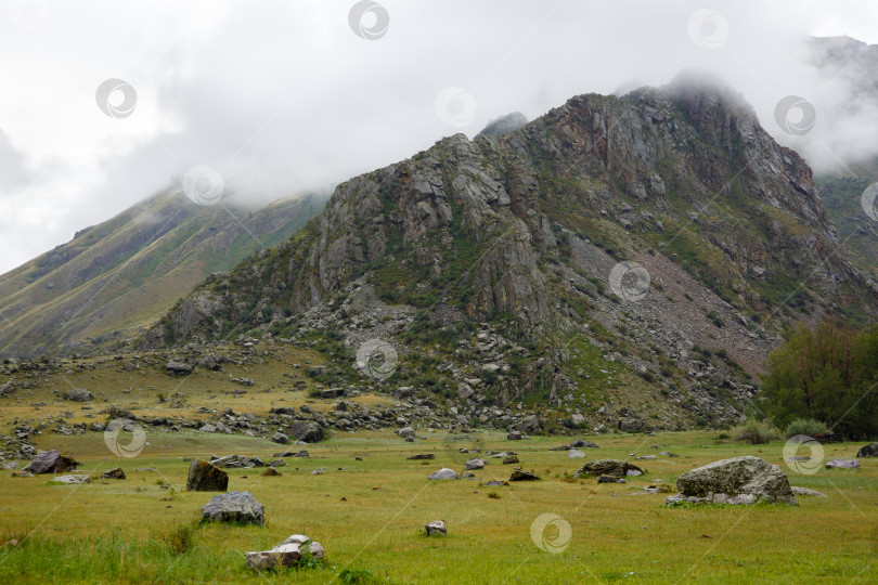 Скачать Пейзаж - скала в утреннем тумане, окруженная валунами фотосток Ozero