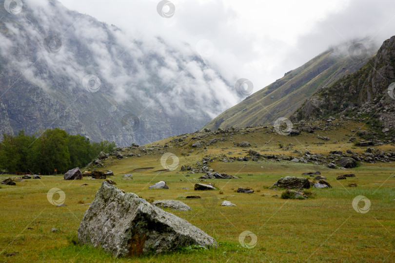Скачать Пейзаж - скала в утреннем тумане, окруженная валунами фотосток Ozero