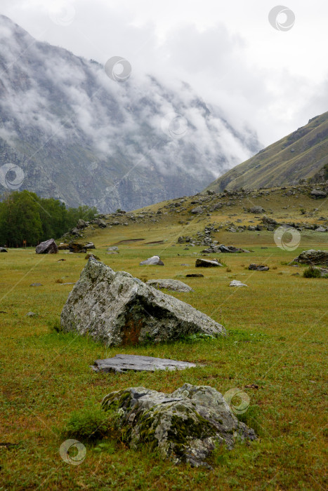 Скачать Пейзаж - скала в утреннем тумане, окруженная валунами фотосток Ozero