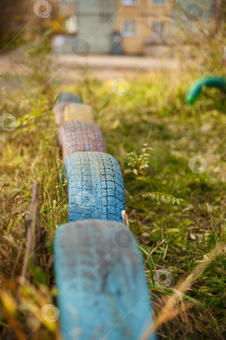 Скачать старая игровая площадка из раскрашенных покрышек, закопанная в землю фотосток Ozero