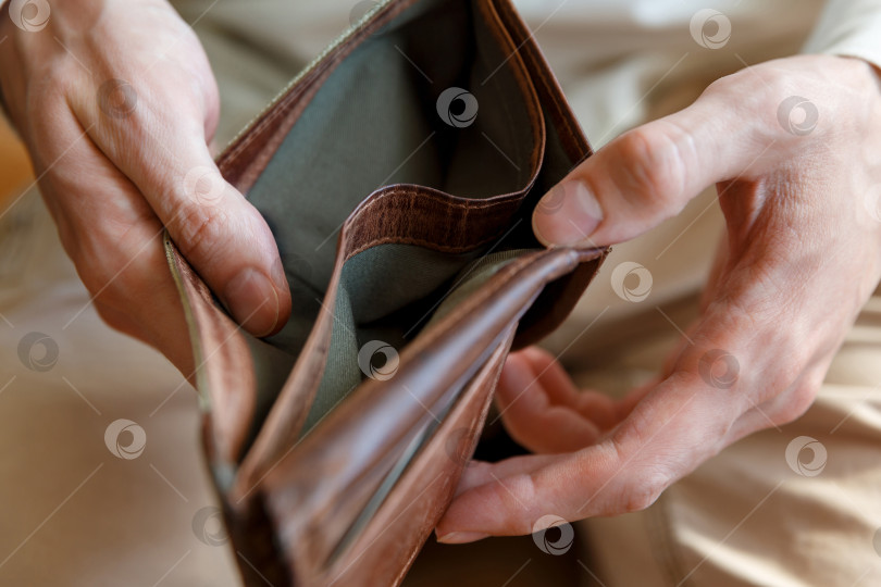 Скачать Пустой бумажник в руках мужчины на простом фоне фотосток Ozero