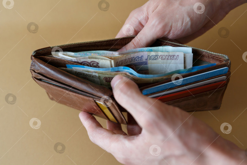 Скачать Кошелек с деньгами в руках мужчины на светлом фоне фотосток Ozero