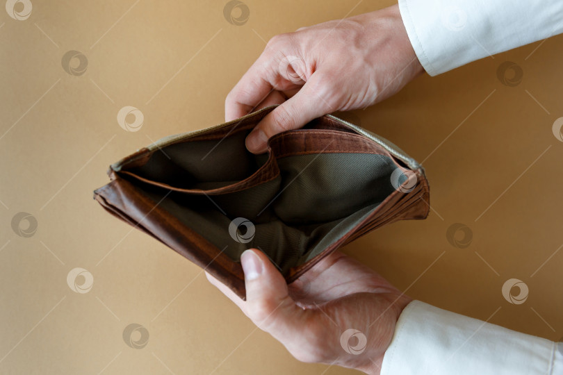 Скачать Пустой бумажник в руках мужчины на простом фоне фотосток Ozero