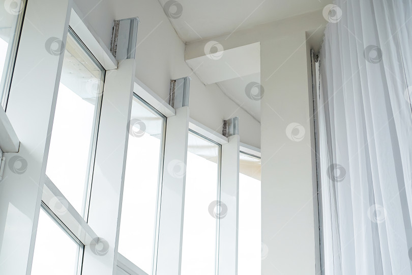 Скачать высокие белые пластиковые панорамные окна и белые шторы в светлой квартире фотосток Ozero