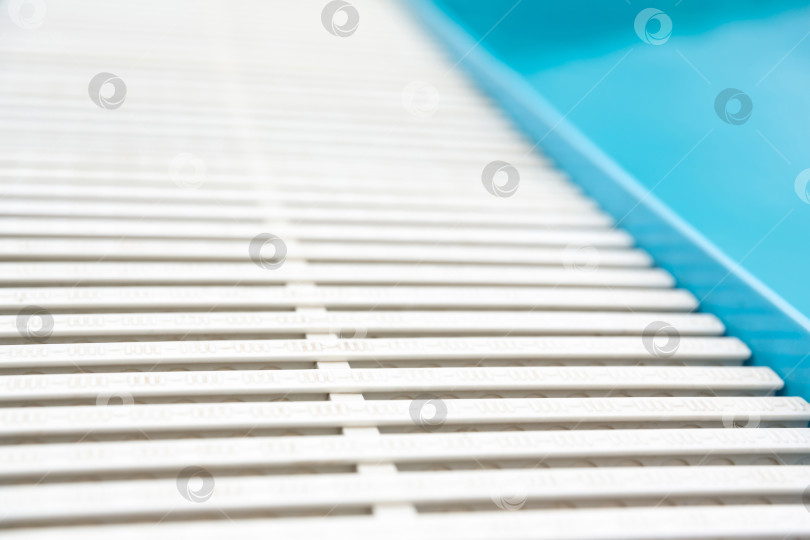 Скачать голубая прозрачная поверхность воды в бассейне и белая пластиковая боковая решетка фотосток Ozero