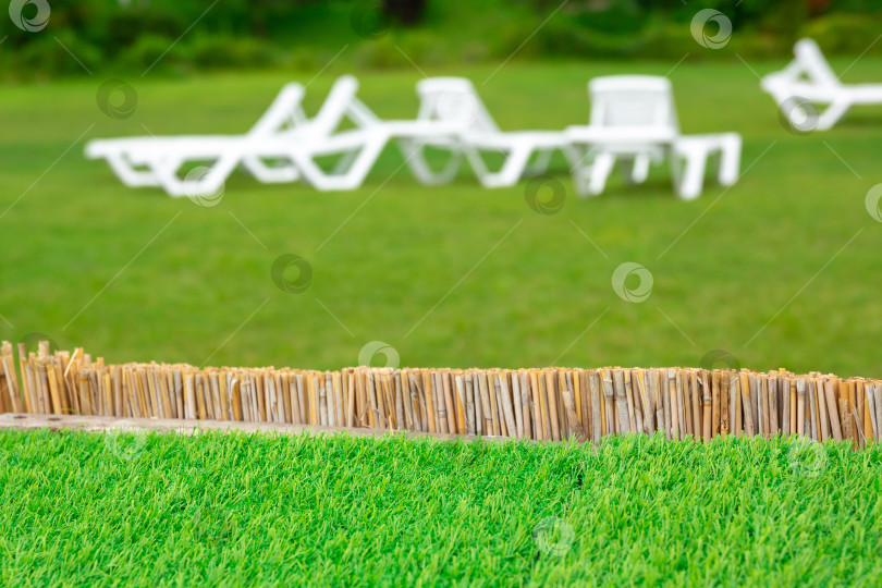 Скачать шаблон для размещения продукта. Фон или задник. Зеленая газонная трава на фоне белого пластикового шезлонга фотосток Ozero