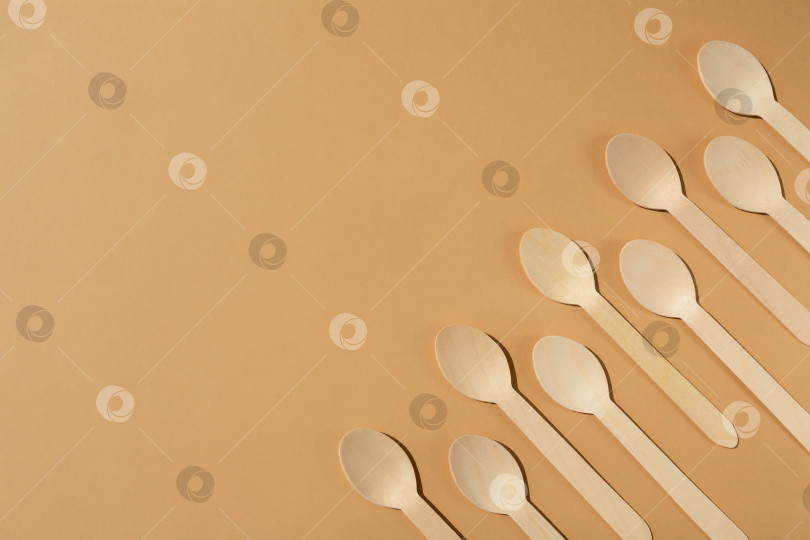 Скачать Деревянные ложки на бежевом фоне. Контрастное освещение. Ровная поверхность. Экологически чистые деревянные столовые приборы. Концепция без использования пластика фотосток Ozero