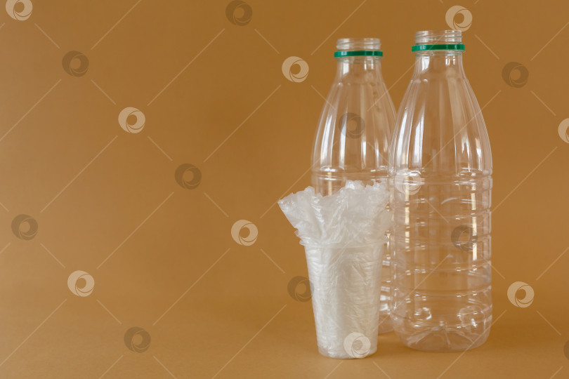 Скачать пластиковые бутылки и полиэтиленовые пакеты в стакане на коричневом фоне фотосток Ozero