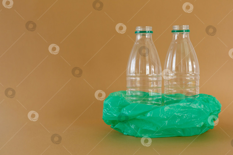 Скачать Пластиковые бутылки в полиэтиленовом пакете на коричневом фоне фотосток Ozero