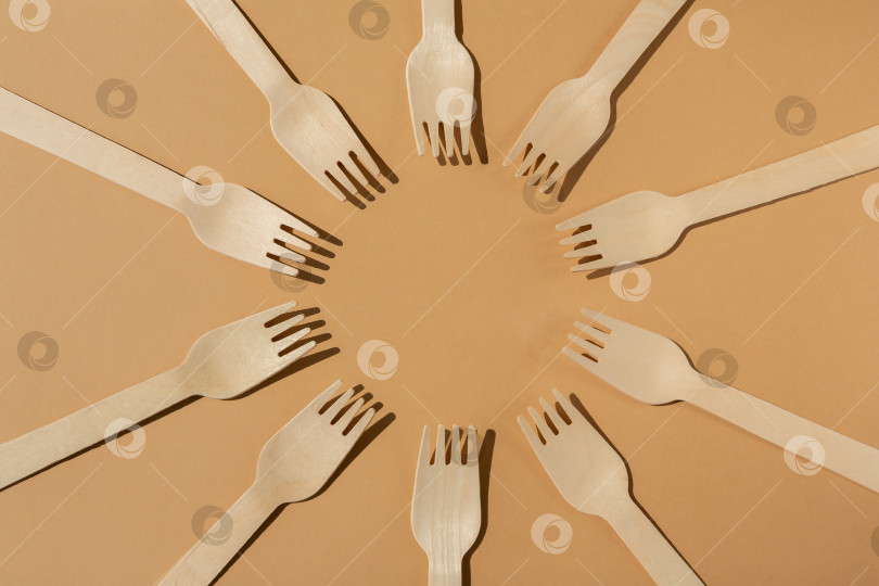 Скачать деревянные вилки разложены по кругу. Контрастное освещение. Плоская форма. Экологически чистые деревянные столовые приборы. Концепция без использования пластика фотосток Ozero