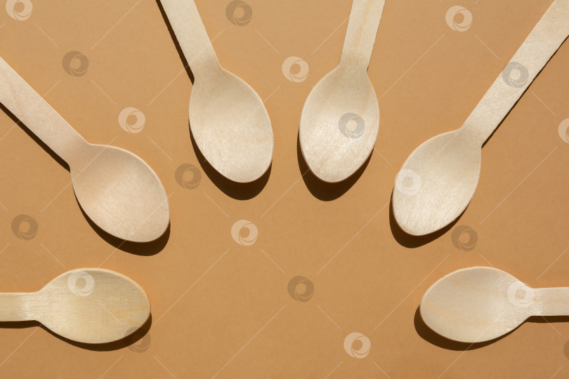 Скачать деревянные ложки разложены по кругу. Контрастное освещение. Ровная поверхность. Экологически чистые деревянные столовые приборы. Концепция без использования пластика фотосток Ozero