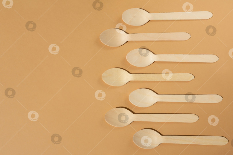 Скачать Деревянные ложки на бежевом фоне. Контрастное освещение. Ровная поверхность. Экологически чистые деревянные столовые приборы. Концепция без использования пластика фотосток Ozero