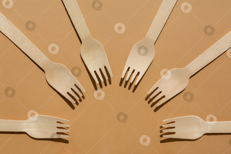 Скачать деревянные вилки разложены по кругу. Контрастное освещение. Плоская форма. Экологически чистые деревянные столовые приборы. Концепция без использования пластика фотосток Ozero