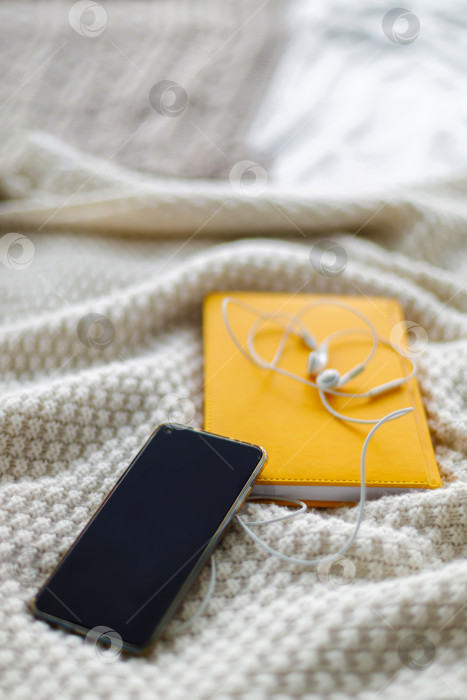 Скачать смартфон и наушники лежат на блокноте. Серый фон фотосток Ozero