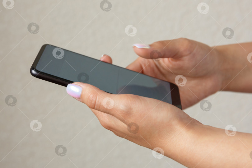 Скачать девушка держит в руках смартфон на светлом фоне фотосток Ozero