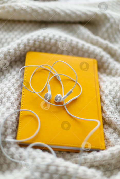 Скачать наушники лежат на блокноте. Серый фон фотосток Ozero