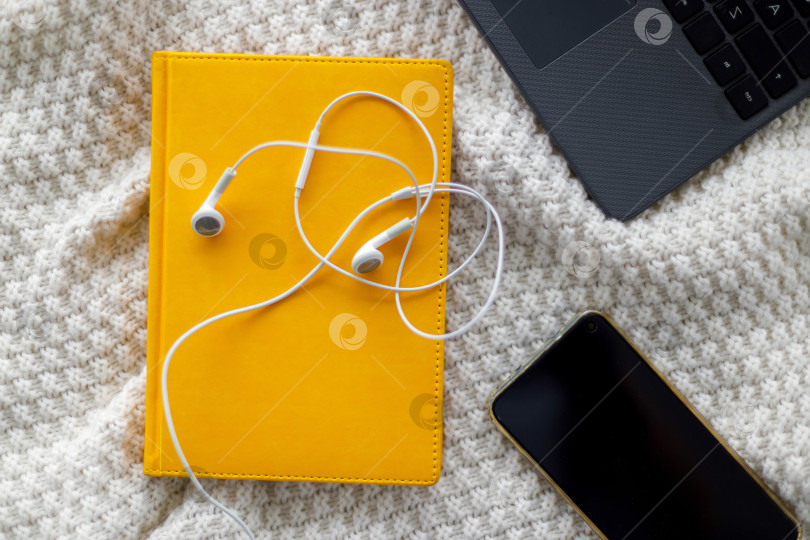 Скачать Ноутбук, блокнот и наушники лежат на вязаном пледе фотосток Ozero