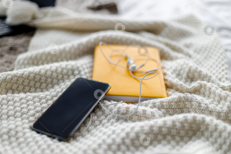 Скачать смартфон и наушники лежат на блокноте. Серый фон фотосток Ozero