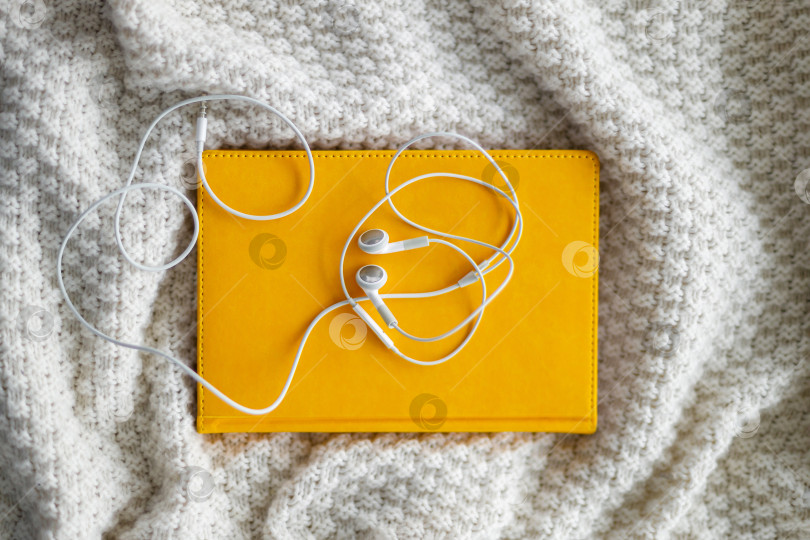 Скачать наушники лежат на блокноте. Серый фон фотосток Ozero