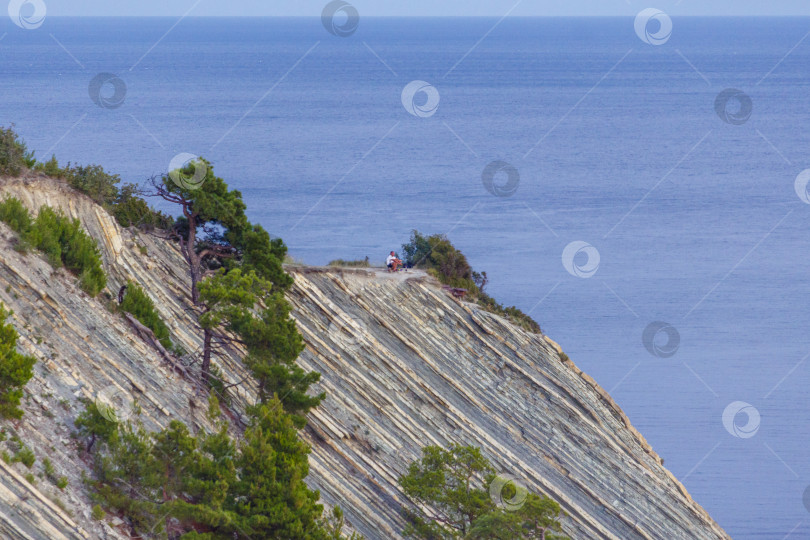 Скачать Курорт Геленджик. Черное море. Мужчина наблюдает за закатом солнца на море с вершины крутой скалистой горы фотосток Ozero