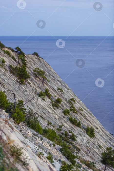Скачать Курорт Геленджик. Черное море. Мужчина наблюдает за закатом солнца на море с вершины крутой скалистой горы фотосток Ozero