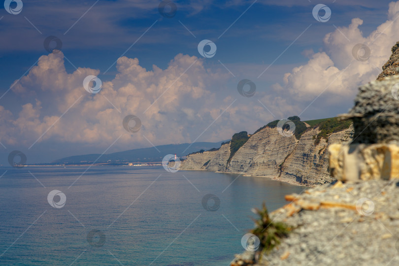 Скачать Курорт Геленджик, пляж Сосновка. Черное море. Высокая белая скала, на вершине которой растут сосны. Пляж у подножия скалы. Маяк на заднем плане фотосток Ozero