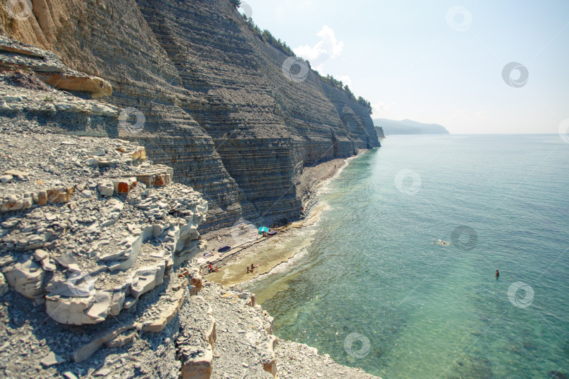Скачать Курот Геленджик. Пляж Сосновка. Высокая белая скала и пляж у подножия обрыва. Чистое теплое море. Люди будут загорать на пляже. фотосток Ozero