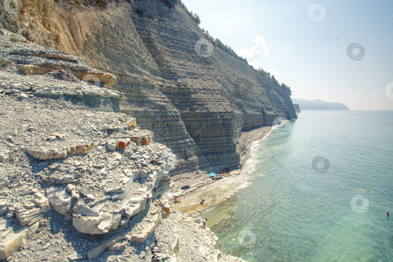 Скачать Курот Геленджик. Пляж Сосновка. Высокая белая скала и пляж у подножия обрыва. Чистое теплое море. Люди будут загорать на пляже. фотосток Ozero
