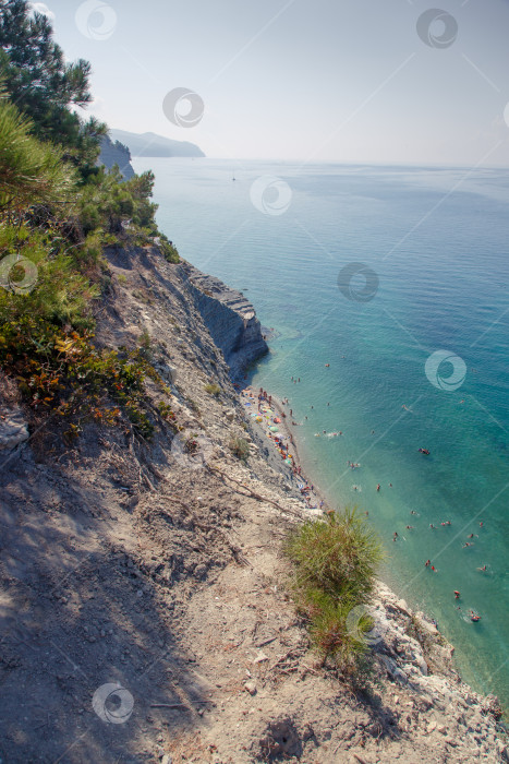Скачать Геленджик. Пляж Сосновка. Высокая белая скала и пляж у подножия обрыва. Чистое теплое море. Люди будут загорать на пляже. фотосток Ozero