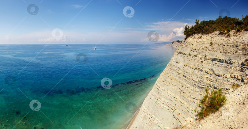 Скачать Большая белая моторная яхта стоит у крутого высокого скалистого берега. На вершине скалы растут сосны. Геленджик, Черное море. Спокойное, гладкое море фотосток Ozero