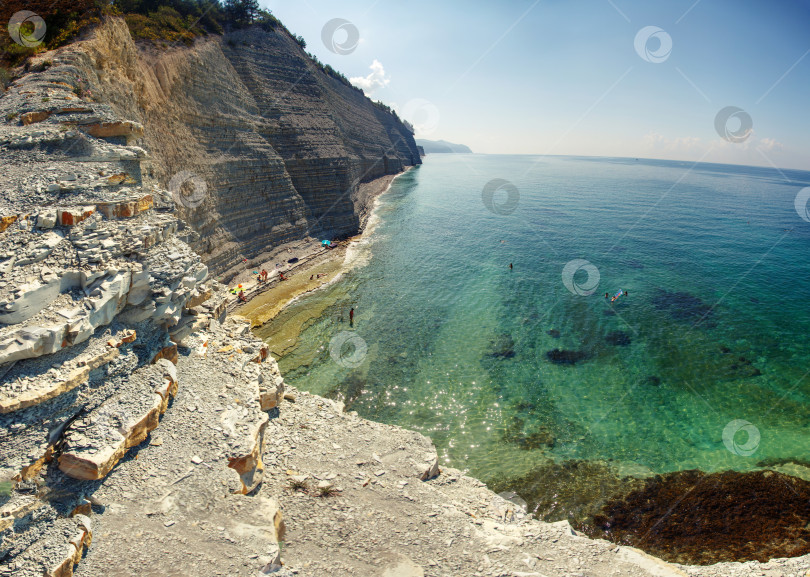 Скачать Курот Геленджик. Пляж Сосновка. Высокая белая скала и пляж у подножия обрыва. Чистое теплое море. Люди будут загорать на пляже. фотосток Ozero