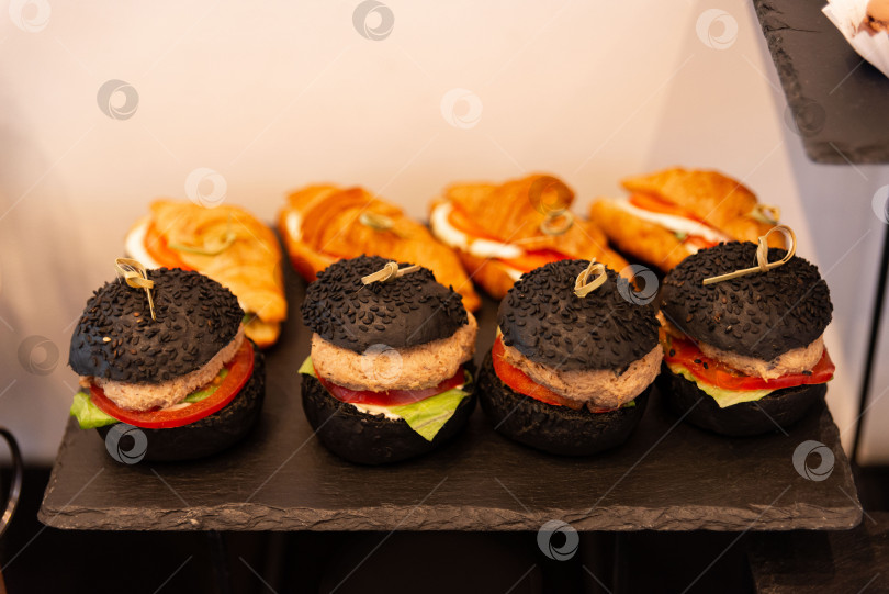 Скачать Витрина с черными бургерами и круассанами для гурманов фотосток Ozero