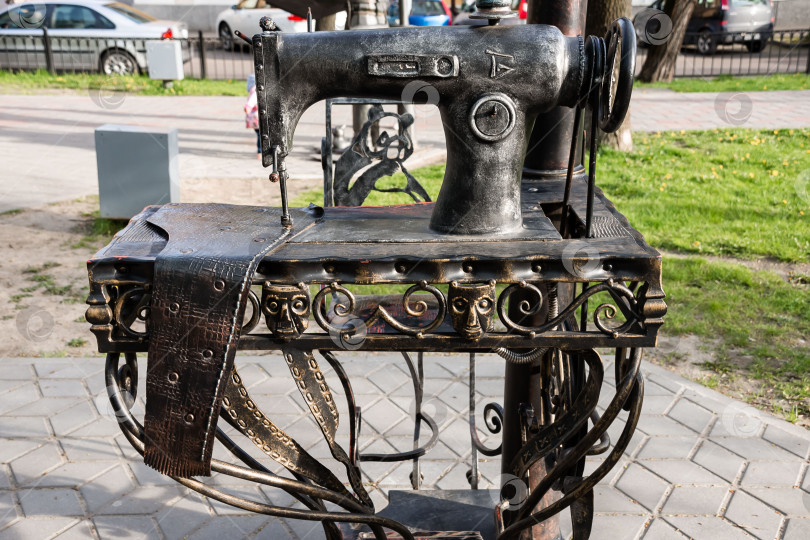 Скачать Старинная металлическая скульптура швейной машинки на открытом воздухе в городской обстановке фотосток Ozero