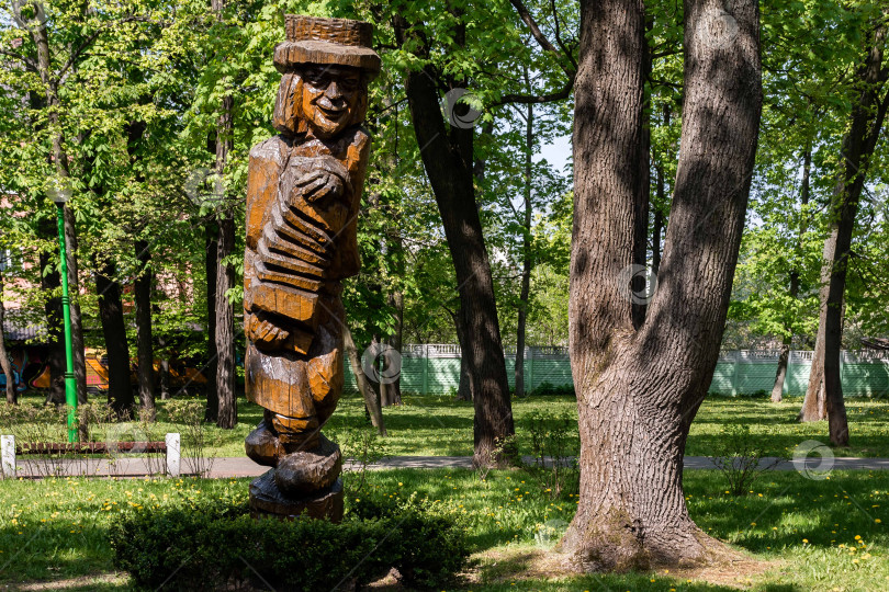 Скачать Деревянная скульптура человека в парке среди деревьев фотосток Ozero