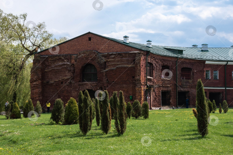 Скачать Историческое кирпичное здание с зеленой лужайкой и деревьями под пасмурным небом фотосток Ozero