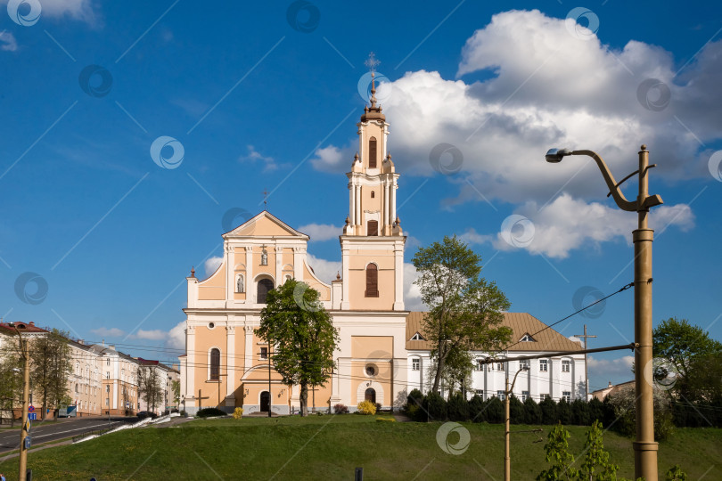 Скачать Католическая церковь в стиле барокко с башней на фоне голубого неба и облаков в городской обстановке фотосток Ozero
