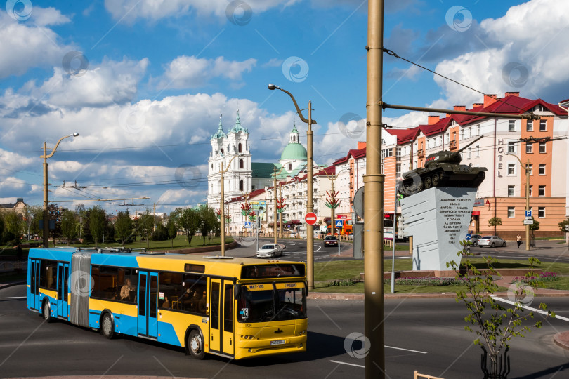 Скачать Желтый городской автобус и исторический памятник в городской среде на фоне голубого неба фотосток Ozero