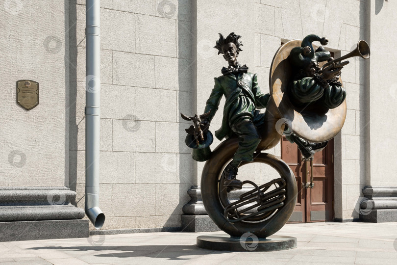 Скачать Причудливая бронзовая скульптура шута, играющего на тубе на городской улице фотосток Ozero