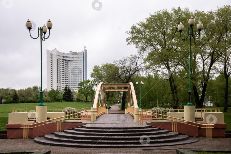 Скачать Городской парковый мост с современным отелем и зелеными окрестностями под облачным небом фотосток Ozero