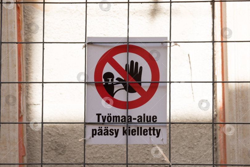 Скачать Предупреждающий знак на строительной площадке на финском языке за металлическим забором фотосток Ozero