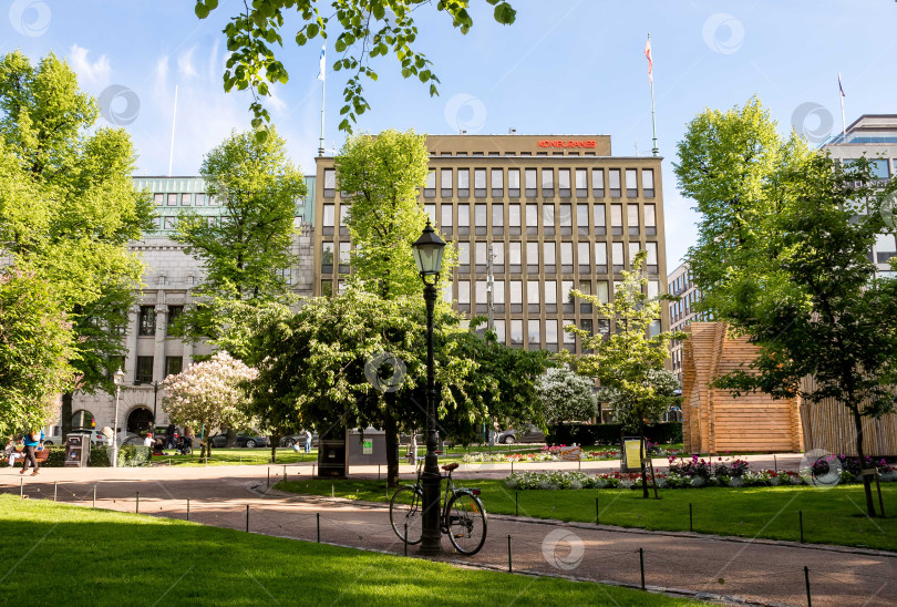 Скачать Солнечный городской парк с велосипедными прогулками и историческими зданиями в Осло фотосток Ozero