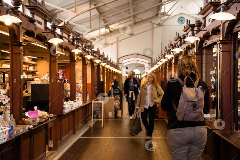 Скачать Оживленный крытый рынок, на котором взрослые кавказцы и азиаты осматривают прилавки фотосток Ozero