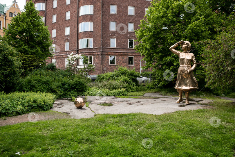 Скачать Бронзовая женская статуя в городском парке рядом с историческим кирпичным зданием фотосток Ozero