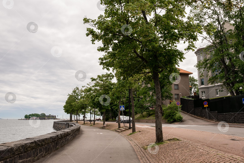 Скачать Живописная прибрежная дорожка с деревьями и кирпичным тротуаром под пасмурным небом фотосток Ozero