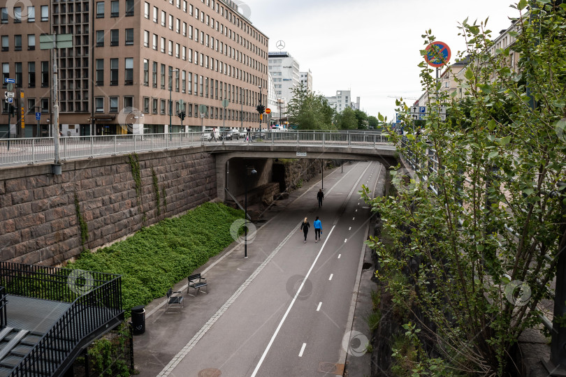 Скачать Городская дорожка под мостом с прогуливающейся парой на фоне городского пейзажа фотосток Ozero