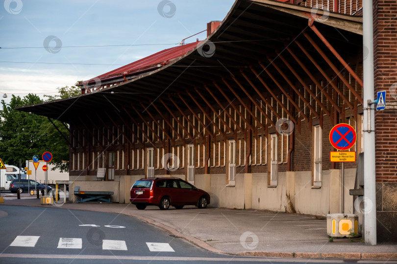 Скачать Исторический склад из красного кирпича с навесом и красной машиной на тихой городской улице фотосток Ozero