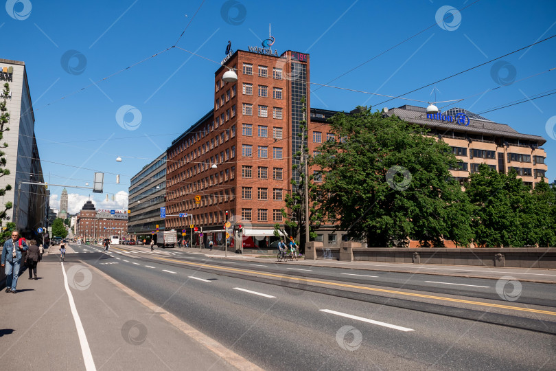 Скачать Оживленная городская улица с кирпичными зданиями и деревьями в солнечный день фотосток Ozero